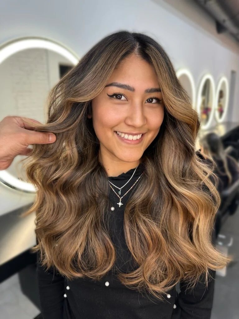 Clienta sonriente con balayage castaño miel hecho en Cosmopolitan